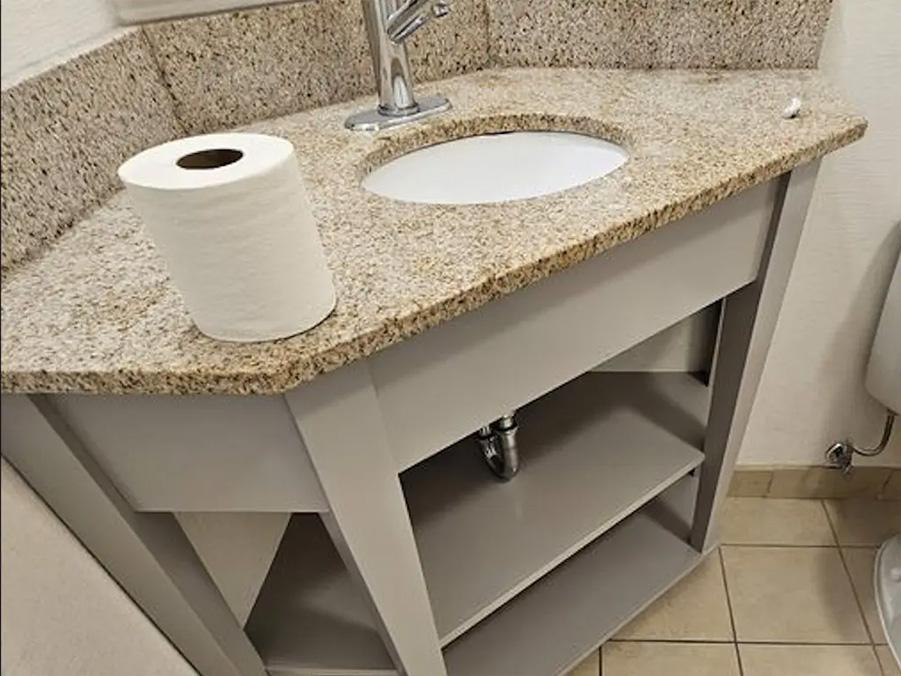 A simple granite countertop above a grey vanity in the corner showcasing the need for regular bathroom vanity repairs to maintain a hygienic look and feel.